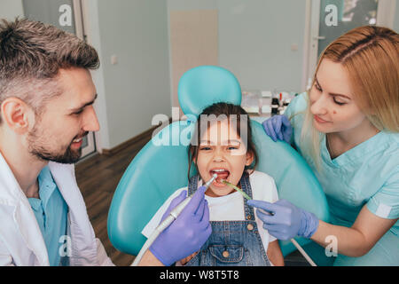 Assistants helping dentist in treatment patient's teeth in medical clinic Stock Photo