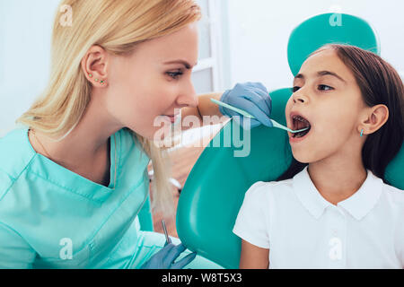 Little girl getting teeth exam by pediatric dentist at clinic Stock Photo