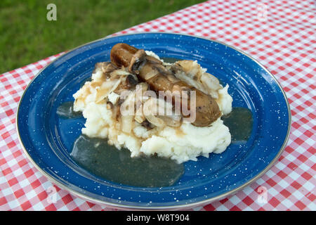 Closeup on Bangers and mash plate with mushrooms on a check red gingham tablecloth in Camping, vegetarian, vegan, meal Stock Photo
