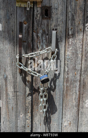 Closeup padlock and secured chain on old door Stock Photo