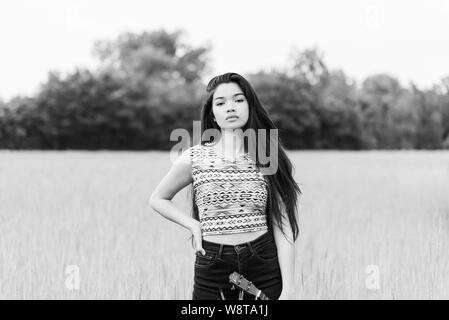 young beautiful asian woman with very long hair and a ukulele outdoors Stock Photo