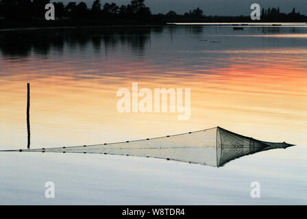 An abstract sunset view of a netted fish trap reflected in the harbor of Bandholm, Denmark Stock Photo