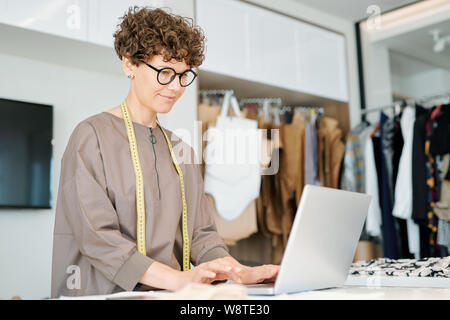 Pretty professional of clothes design standing in front of laptop Stock Photo