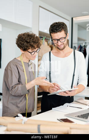 Two young creative designers pointing at touchpad display Stock Photo