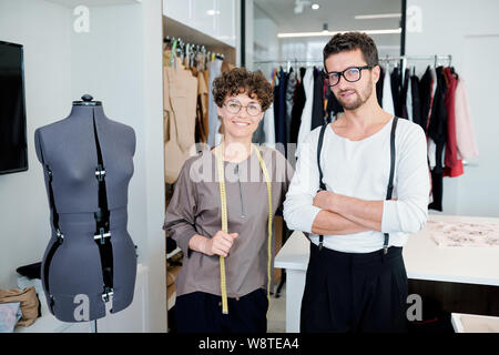 Two happy young creative designers of clothing standing by mannequin Stock Photo