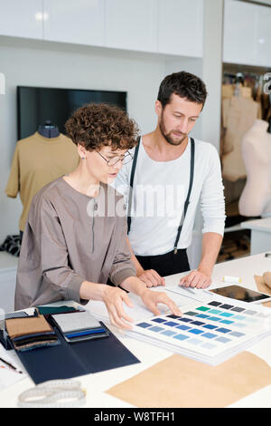 Two young colleagues discussing color swatches by workplace Stock Photo