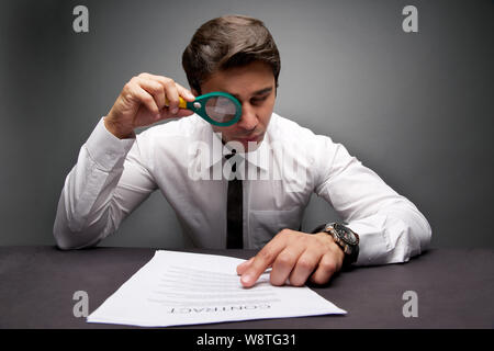 Businessman looking a document through magnifying glass Stock Photo