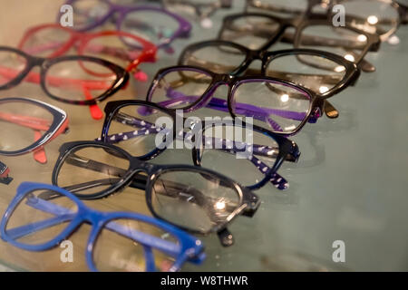 exhibitor of glasses consisting of shelves of fashionable glasses shown on a wall at the optical shop. Colorful Elegant eyeglasses in a store