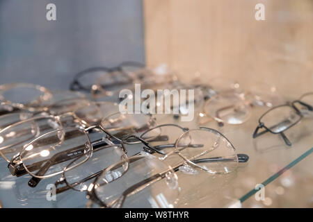 optics, health care and vision concept - close up of eyeglasses at optician.exhibitor of glasses consisting of shelves of fashionable glasses shown on Stock Photo