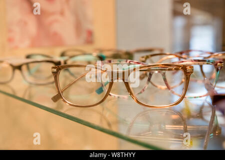 optics, health care and vision concept - close up of eyeglasses at optician.exhibitor of glasses consisting of shelves of fashionable glasses shown on Stock Photo