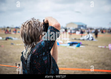 A female photographer taking pictures with a camera at an outdoor event Stock Photo
