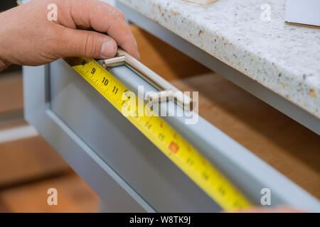 A carpenter is building a man measuring for a drawers in the kitchen cabinets Stock Photo