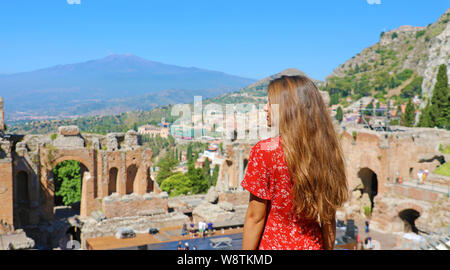 Beautiful young female model in the ruins of the ancient Greek theater in Taormina with the Etna volcano on the background, Sicily, Italy Stock Photo