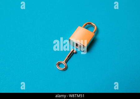 Flat lay protection concept. Locked padlock and key on the blue background. Stock Photo