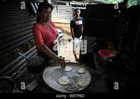 August 8, 2019, La Reforma, San Marcos, Guatemala: Eight days after being deported from the U.S., Lisardo Perez stands by the kitchen watching his mother Elida Esperanza cooking tortillas,early in the morning at their house in the Canton La Palma neighborhood, in La Reforma, Guatemala.Â After 8 years of falling coffee prices, 4 off a steady job from his father, and 3 years watching his younger brother Edgar Giovani suffer a debilitatingÂ illness that left the family in medical debt, they put all their hope in Lisardoâ€” taking an $8000 loan against their house to pay a smuggler to take him to Stock Photo