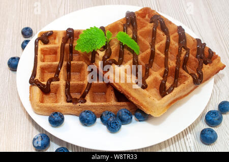 Belgian waffles on a plate with chocolate sauce and blueberries Stock Photo