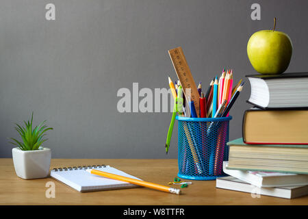 Back to school concept, school supplies, stack of books, green apple, succulent in a white pot and an open notebook on wooden surface, selective focus Stock Photo