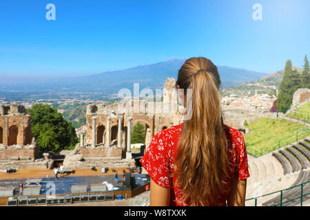 Beautiful young female model in the ruins of the ancient Greek theater in Taormina with the Etna volcano on the background, Sicily Italy Stock Photo