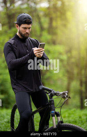 Happy bearded man cyclist rides in the sunny forest on a mountain bike. Stock Photo
