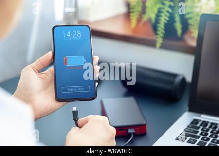 Woman charges her smartphone with power bank using fast charge  USB-C cable. Interface on the screen was created in graphic program. Stock Photo