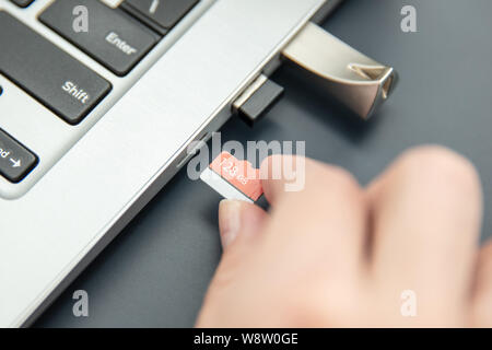 Woman's hand puts in fast, capacoius microSD card to the modern ultrabook. Stock Photo
