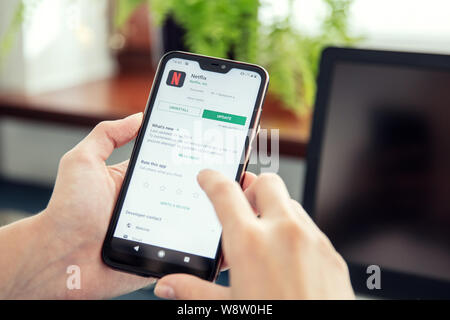 WROCLAW, POLAND - JULY 31th, 2019: Woman installs Netflix application on the Xiaomi A2 smartphone. Netflix is an American media-services provider whic Stock Photo