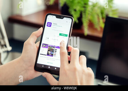 WROCLAW, POLAND - JULY 31th, 2019: Woman installs Netflix application on the Xiaomi A2 smartphone. Twitch is a live streaming video platform owned by Stock Photo