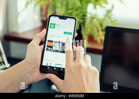 WROCLAW, POLAND - JULY 31th, 2019: Woman installs Netflix application on the Xiaomi A2 smartphone. Xbox is a video gaming brand created and owned by M Stock Photo