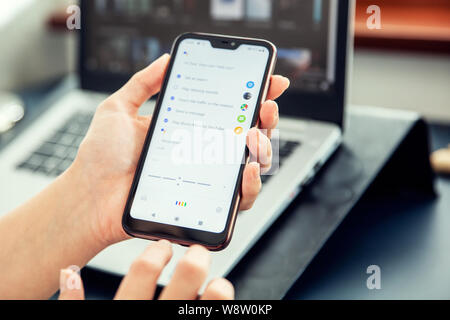WROCLAW, POLAND - JULY 31th, 2019: Woman uses google assistant on xiaomi a2 smartphone. Google Assistant is an artificial intelligence-powered virtual Stock Photo
