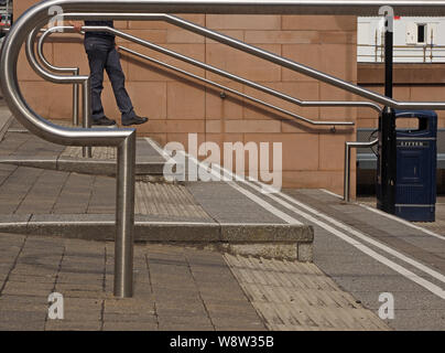 figure walking down steps amid modern curved shiny stainless steel railings at a campus in Dundee, Scotland, UK Stock Photo