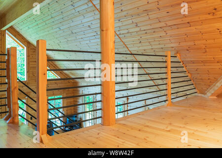 Black tubular railings with wooden post in home office set-up on mezzanine inside a piece sur piece Scots pine log home Stock Photo