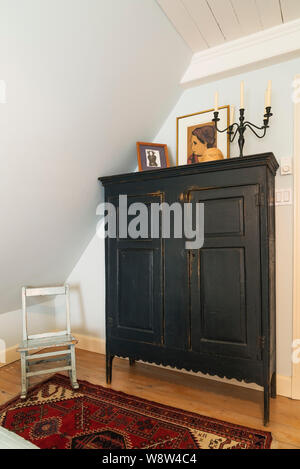 Antique wooden armoire and child's rocking chair on rug in second upstairs master bedroom with pinewood floor inside an old renovated 1650s house Stock Photo