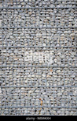 Abstract architectural background of rough retaining wall made from rocks in steel cage gabion baskets Stock Photo