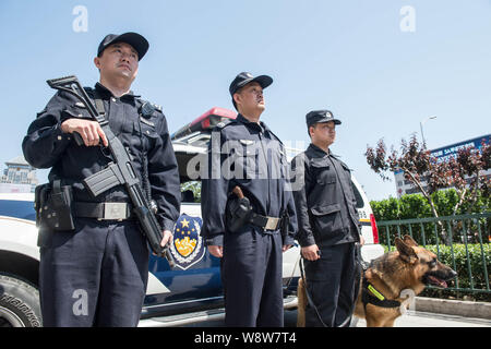 Chinese police officers armed with guns stand guard with a police dog in front of a patrol vehicle on a street in Beijing, China, 12 May 2014.   Beiji Stock Photo