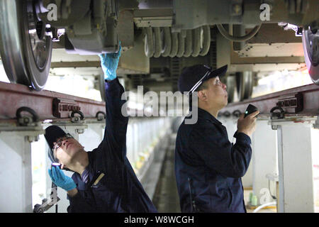 Chinese workers examine a CRH (China Railway High-speed) train at a maintenance station in Shenzhen city, south Chinas Guangdong province, 17 January Stock Photo