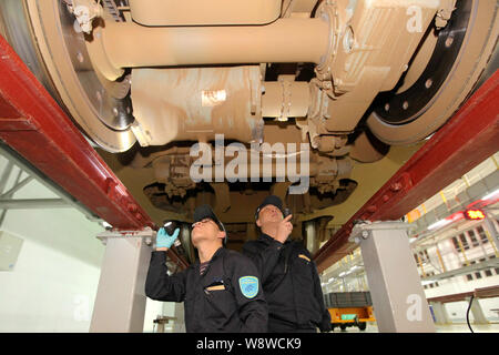 Chinese workers examine a CRH (China Railway High-speed) train at a maintenance station in Shenzhen city, south Chinas Guangdong province, 17 January Stock Photo