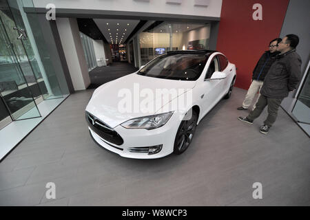 --FILE--Visitors look at a white Model S electric car on display at the Tesla store in Beijing, China, 5 November 2013.   In China, where higher price Stock Photo