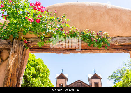 Famous El Santuario de Chimayo sanctuary church in the United States with entrance gate closeup of flowers in summer Stock Photo