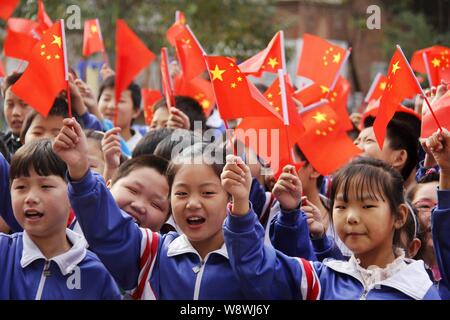 Young Chinese students wave small Chinese national flags to celebrate the National Day holiday at a primary school in Guangping county, north China's Stock Photo