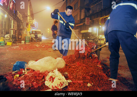 Chinese cleaning workers clear away scraps of fireworks and firecrackers on a street on the first day of the Chinese Lunar New Year holiday or Spring Stock Photo