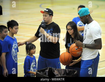 NBA superstar LeBron James, right, signs autographs on basketballs for fans during a fan meeting of the Rise 2014 LeBron James Basketball Tour in Hong Stock Photo