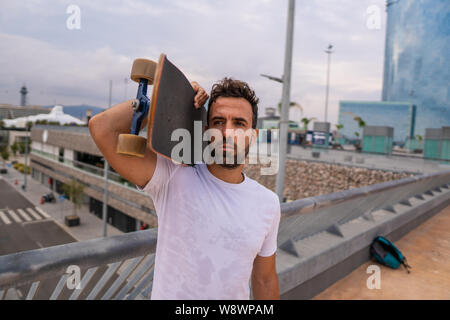 Skateboarder stands with skateboard in the modern city terrace Stock Photo