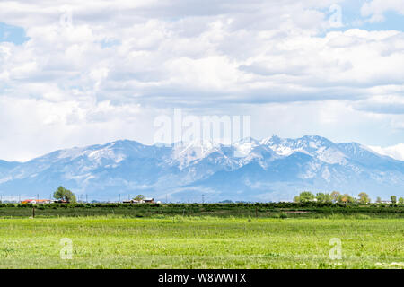 Highway South County Road 100 with rural countryside farms in Monte Vista, Colorado and view of Rocky Mountains Stock Photo