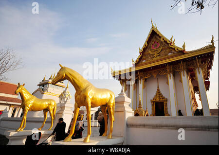 Tourists walk past horse sculptures before a Thai-style Buddhist temple within the area of White Horse Temple, or Bai Ma Si, in Luoyang city, central Stock Photo