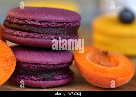 Two purple French macarons or macaroons with half of an apricot closeup. Selective focus, shallow dof. Stock Photo