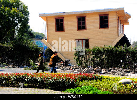 Visitors walk past an upside-down house under construction at China Folk Painting Village in Fengjing Ancient Town, Jinshan District, Shanghai, China, Stock Photo