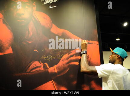 NBA superstar LeBron James signs his autograph on a giant poster during a fan meeting of the Rise 2014 LeBron James Basketball Tour in Hong Kong, Chin Stock Photo