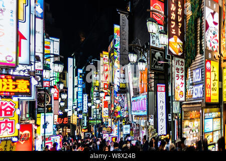 Shinjuku, Japan - April 3, 2019: People walking on famous red light district Kabukicho alley street in downtown city with neon bright lights at night Stock Photo
