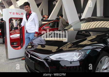 People look at Tesla Model S electric cars delivered to their owners at the sales center of Tesla in Jinqiao, Shanghai, China, 23 April 2014.   Seven Stock Photo