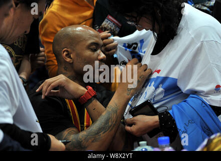 American basketball player Stephon Marbury of Chinas Beijing Ducks, center, signs on the T-shirt of a Chinese fan at a celebration party for Beijing D Stock Photo